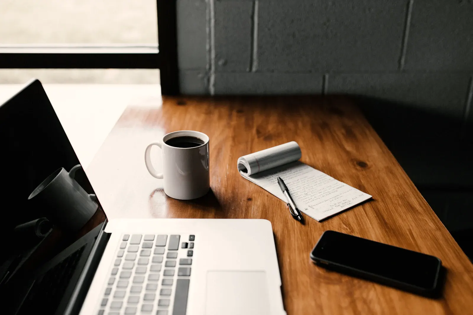 A quiet desk with a notebook and coffee in morning light.
